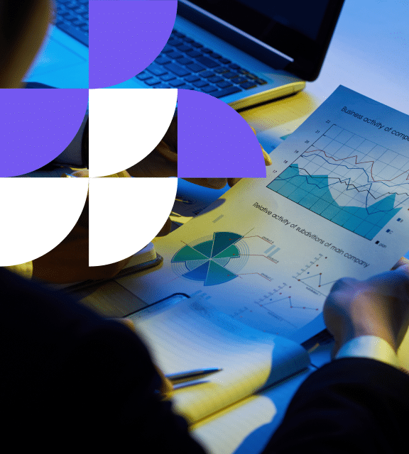 a person looking at a paper with data analytics consulting graphs and a laptop